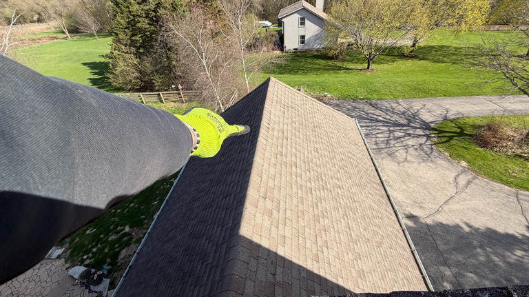 Aerial view of a technician clearing a roof gutter